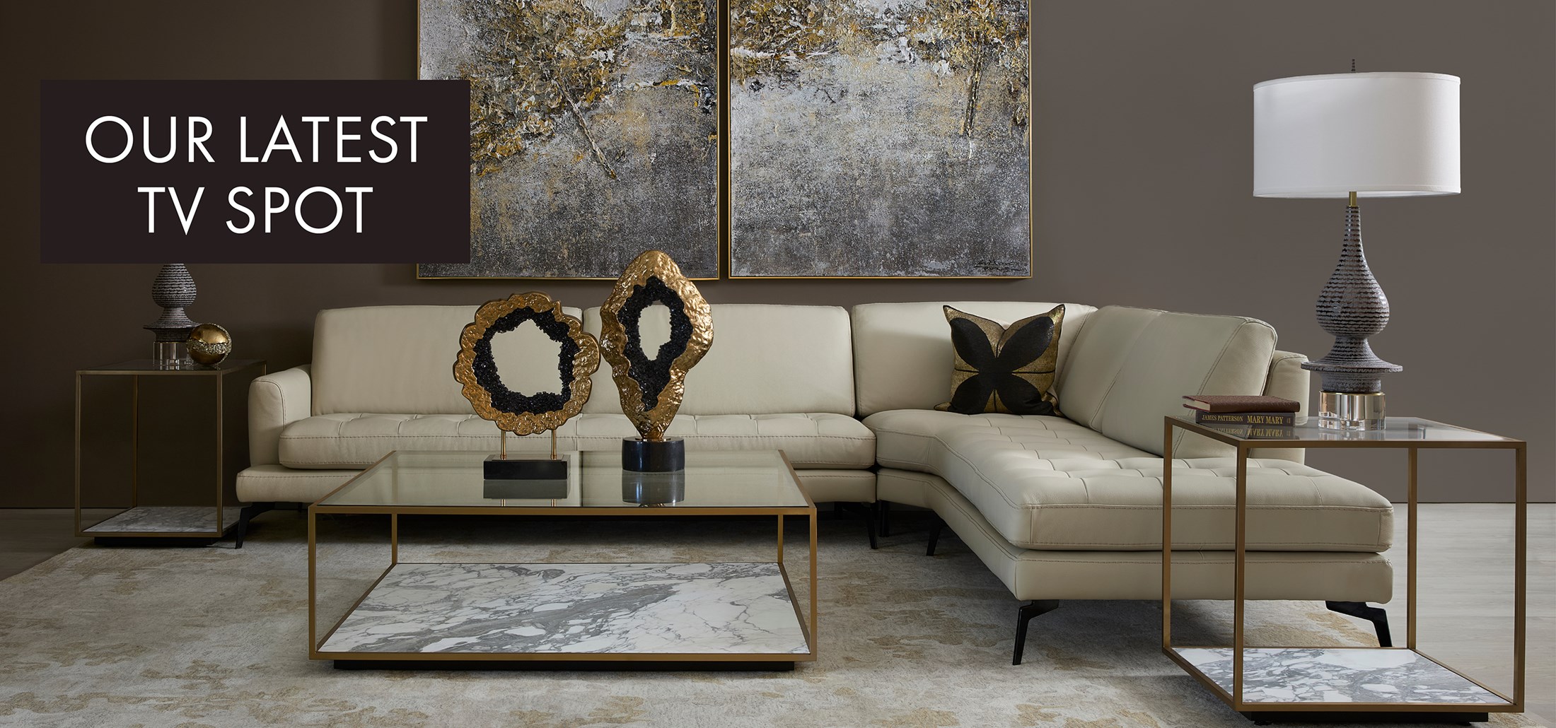 Image of the Living Sectional with marble tables and gold and black decor. Text: Text: Our Latest TV Spot. Links to TV Spot on Youtube.