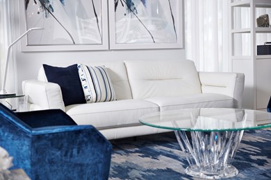 a photo of a living room vignette featuring a contemporary white leather sofa and a blue velvet chair 