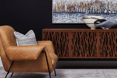 a photo of a tan leather chair with and industrial looking media cabinet accented with artwork and accessories